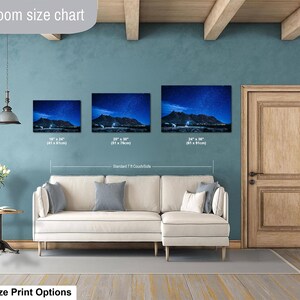Puede incluir: Una tabla de tama&ntilde;os para sala de estar que muestra tres impresiones de arte mural horizontal sobre un sof&aacute; seccional color crema. Las im&aacute;genes muestran un paisaje monta&ntilde;oso nocturno bajo un cielo estrellado, con medidas de 41x61cm, 51x76cm y 61x91cm.