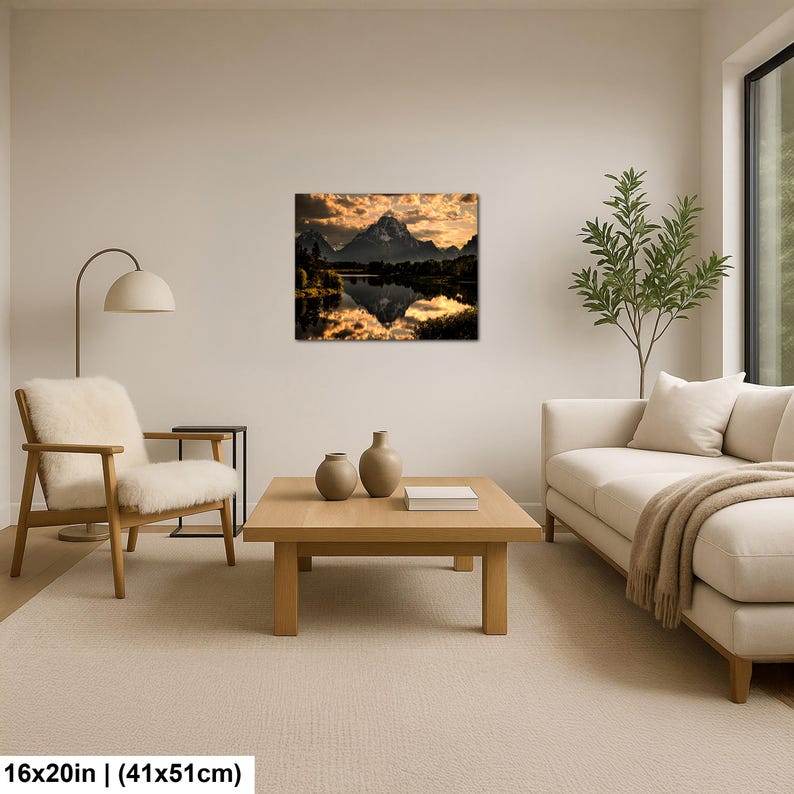 Puede incluir: Una impresi&oacute;n de arte mural rectangular que muestra un paisaje de monta&ntilde;a al atardecer con luz dorada reflej&aacute;ndose en la superficie de un lago tranquilo. La obra mide 41 cm por 51 cm y se exhibe en una pared sobre una mesa de centro.
