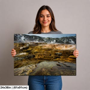 K&ouml;nnte beinhalten: Ein rechteckiger Wandkunstdruck in der Gr&ouml;&szlig;e 61 x 91 cm, der eine Landschaftsaufnahme von geothermischen Terrassen mit geschichteten, goldbraunen Mineralablagerungen, Wasserbecken und aufsteigendem Dampf vor felsigen H&uuml;geln zeigt.