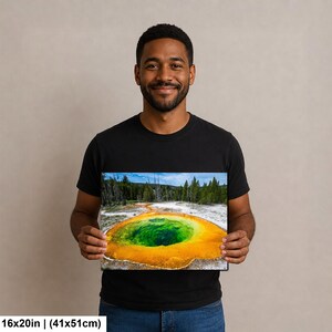 May include: A rectangular wall art print featuring a vibrant geothermal hot spring with a deep green center surrounded by bright orange and yellow mineral deposits, set against a forest backdrop, measuring 16 inches by 20 inches.