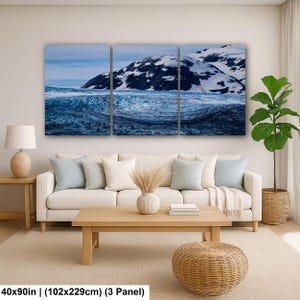 May include: A three-panel wall art set depicting a snowy mountain landscape with a dark, textured glacier in the foreground. The artwork measures 40x90 inches in total. The scene features deep blue and white tones across the three canvas sections.