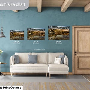 K&ouml;nnte beinhalten: Eine Gr&ouml;&szlig;entabelle f&uuml;r Wohnzimmer zeigt drei Landschafts-Wandbilder &uuml;ber einem cremefarbenen Ecksofa. Die Drucke zeigen eine geothermische Landschaft und sind mit den Ma&szlig;en 41 x 61 cm, 51 x 76 cm und 61 x 91 cm beschriftet.