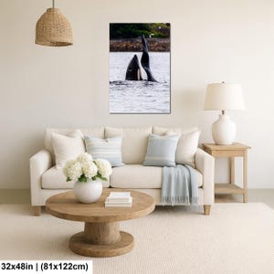 May include: A vertical wall art print featuring a black and white orca whale surfacing in the water with its dorsal fin visible. The artwork measures 32 inches by 48 inches and is displayed in a living room setting above a beige sofa.