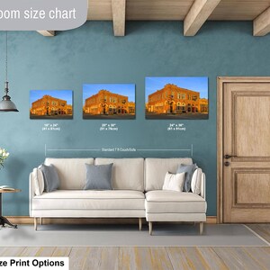 May include: A living room size chart displaying three rectangular wall art prints of a historic orange brick building. The prints are labeled with dimensions of 16 x 24 inches, 20 x 30 inches, and 24 x 36 inches, positioned above a white sectional sofa.