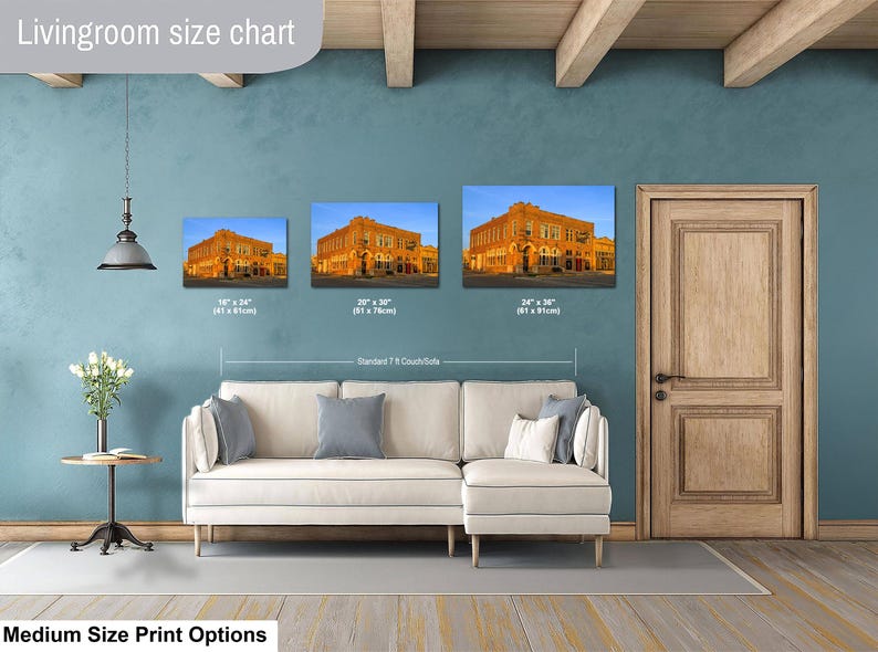 May include: A living room size chart displaying three rectangular wall art prints of a historic orange brick building. The prints are labeled with dimensions of 16 x 24 inches, 20 x 30 inches, and 24 x 36 inches, positioned above a white sectional sofa.