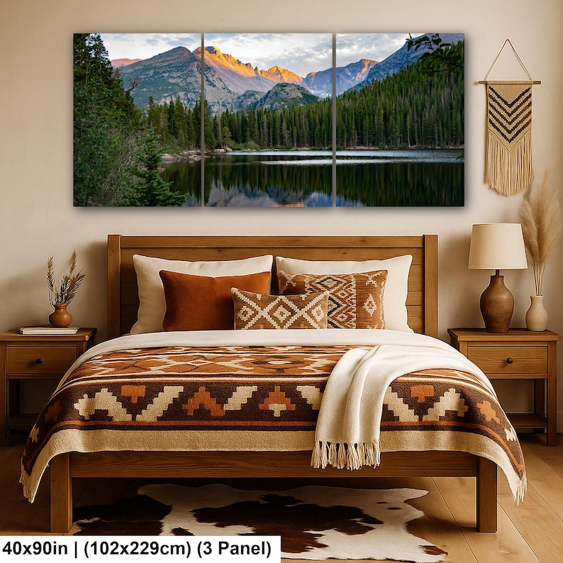 May include: A three-panel wall art set depicting a mountain lake landscape at sunrise, featuring snow-capped peaks, dense pine forests, and water reflections. The artwork measures 40 by 90 inches and is displayed above a wooden bed with patterned bedding.