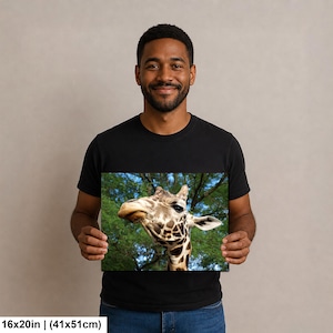 K&ouml;nnte beinhalten: Ein rechteckiger Wandkunstdruck mit den Ma&szlig;en 41 mal 51 cm, der eine Nahaufnahme des Kopfes und Halses einer Giraffe vor einem Hintergrund aus gr&uuml;nen Baumzweigen und blauem Himmel zeigt. Die Giraffe hat braune Flecken und ein helles Maul.
