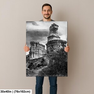May include: A rectangular wall art print measuring 30 by 40 inches, featuring a black and white landscape photograph of tall, weathered rock formations under a cloudy sky, with dark, sparse vegetation in the foreground of the scene.