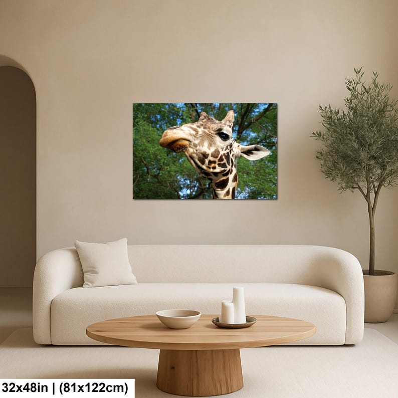 K&ouml;nnte beinhalten: Ein rechteckiger Wandkunstdruck mit einer Nahaufnahme eines Giraffenkopfes mit braun-cremefarbenem Musterfell vor einem Hintergrund aus gr&uuml;nen Baumbl&auml;ttern und blauem Himmel. Der Druck misst 81 cm mal 122 cm, wie im Text angegeben.
