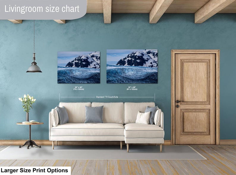 May include: A living room size chart displaying two landscape wall art prints of a snowy mountain above a dark blue ocean wave. The prints are labeled with dimensions of 30 by 40 inches and 32 by 48 inches, positioned above a cream-colored sectional sofa.