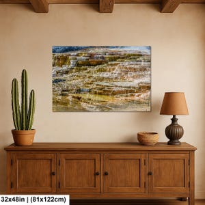 May include: A rectangular wall art print featuring a landscape of layered mineral terraces with shades of orange, brown, and white. The artwork measures 32 inches by 48 inches and is displayed on a wall above a wooden cabinet with a cactus and lamp.