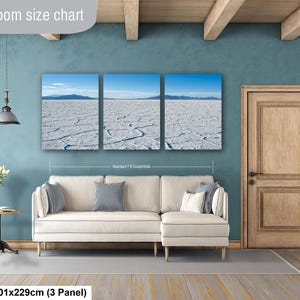 May include: A three-panel canvas wall art set depicting a white salt flat landscape under a blue sky, displayed above a cream-colored sectional sofa. The text Livingroom size chart and 40x90in | 101x229cm (3 Panel) is visible on the image.