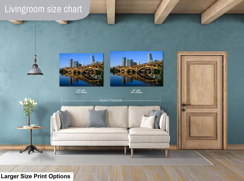 May include: A living room size chart displaying two rectangular wall art prints of a city skyline and bridge over water. The prints are labeled with dimensions of 30 x 40 inches and 32 x 48 inches, positioned above a white sectional sofa.