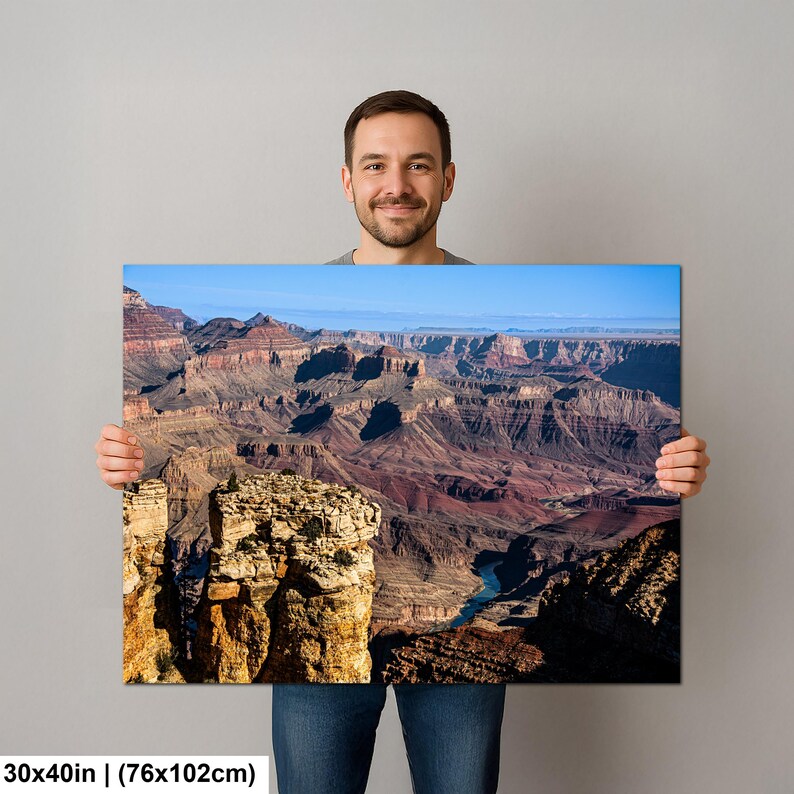 May include: A rectangular wall art print measuring 30 by 40 inches, featuring a high-resolution landscape photograph of the Grand Canyon. The image displays layered rock formations in shades of red, brown, and tan, with a blue river below.