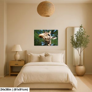 K&ouml;nnte beinhalten: Ein rechteckiger Wandkunstdruck mit einer Nahaufnahme eines Giraffenkopfes mit braun-wei&szlig; gemustertem Fell vor einem Hintergrund aus gr&uuml;nen B&auml;umen und blauem Himmel. Der Druck misst 61 cm mal 91 cm und h&auml;ngt &uuml;ber einem Bett.