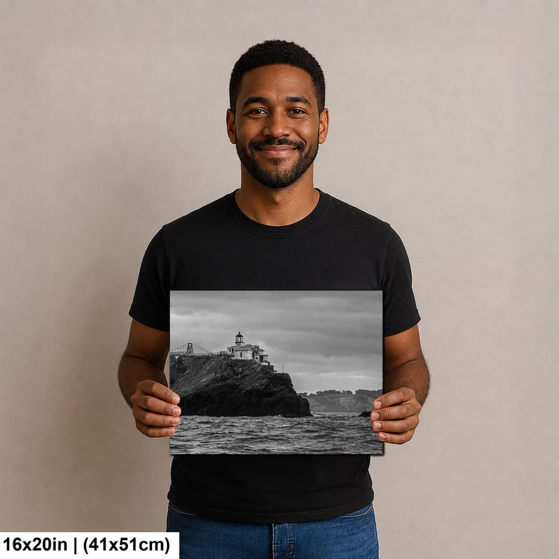 May include: A black and white rectangular print measuring 16x20 inches, featuring a lighthouse perched on a dark, rocky cliffside overlooking the ocean under a cloudy sky. The image captures the structure and the surrounding coastal landscape.