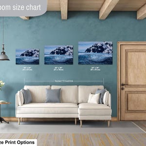 May include: A living room size chart displaying three rectangular wall art prints featuring a snowy mountain landscape above a blue ocean wave. The prints are labeled with dimensions of 16x24 inches, 20x30 inches, and 24x36 inches, shown above a sofa.