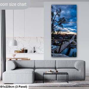 May include: A three-panel wall art set depicting a bridge over water at twilight with a dramatic blue and orange sky. The artwork is displayed above a gray sofa in a room. The text Livingroom size chart and 40x90in are visible in the image.