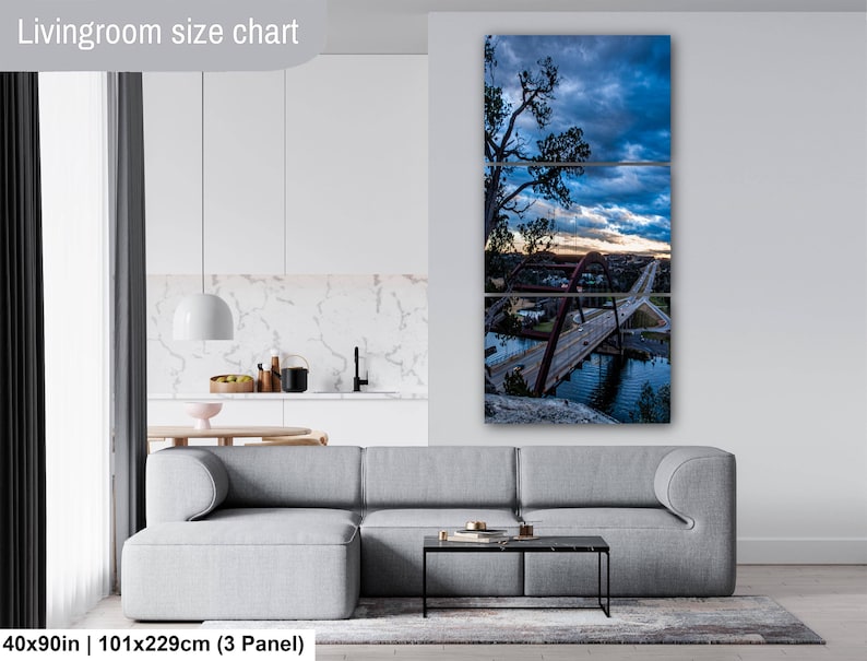 May include: A three-panel wall art set depicting a bridge over water at twilight with a dramatic blue and orange sky. The artwork is displayed above a gray sofa in a room. The text Livingroom size chart and 40x90in are visible in the image.