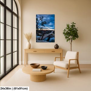 May include: A vertical wall art print measuring 24x36 inches, featuring a landscape photograph of a large arched bridge spanning a river at dusk. The sky is filled with deep blue clouds and a golden horizon, with a tree silhouette on the left.