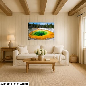 May include: A rectangular wall art print featuring a vibrant geothermal pool with a deep green center surrounded by bright orange and yellow mineral deposits, set against a backdrop of dark green pine trees and a clear blue sky, measuring 32x48 inches.