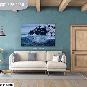 May include: A rectangular wall art print featuring a snowy mountain landscape above a dark blue ocean wave. The print is labeled 40x60in and 101x152cm, with text reading Livingroom size chart and Standard 7 ft Couch/Sofa visible on the display.