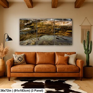 K&ouml;nnte beinhalten: Ein dreiteiliges Wandbild, das eine Landschaft aus terrassenf&ouml;rmigen Mineralbecken in Braun-, Gold- und Wei&szlig;t&ouml;nen zeigt. Das Kunstwerk misst 91 mal 183 cm und ist &uuml;ber einem braunen Ledersofa in einem Raum mit Kaktus angebracht.