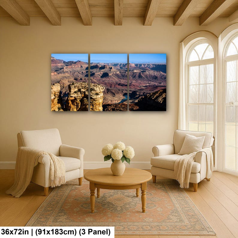 May include: A three-panel wall art set depicting a panoramic view of the Grand Canyon with layered rock formations in shades of brown, orange, and red under a clear blue sky. The total dimensions are 36 by 72 inches for the three panels.