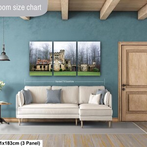 Op de afbeelding: Een driedelige wandkunstset met een stenen kasteel in een mistig bos, weergegeven boven een cr&egrave;mekleurige hoekbank. De tekst 'Livingroom size chart' en '36x72in | 91x183cm (3 Panel)' is zichtbaar op de afbeelding.