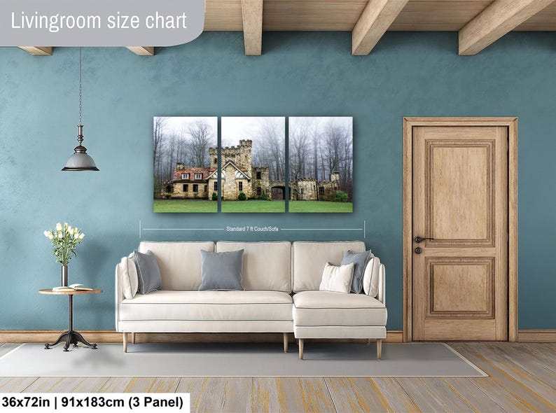 Op de afbeelding: Een driedelige wandkunstset met een stenen kasteel in een mistig bos, weergegeven boven een cr&egrave;mekleurige hoekbank. De tekst 'Livingroom size chart' en '36x72in | 91x183cm (3 Panel)' is zichtbaar op de afbeelding.