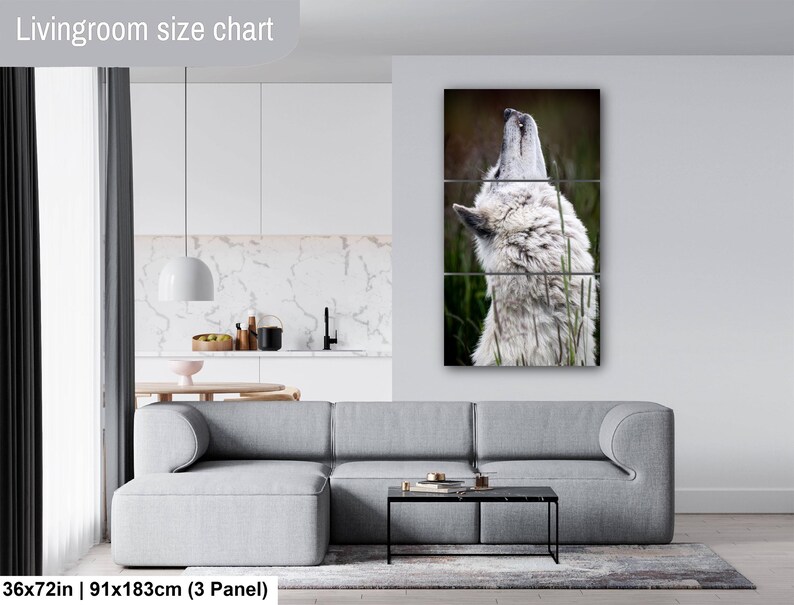 Pu&ograve; includere: Un set di arte da parete a tre pannelli raffigurante un lupo bianco che ulula, esposto sopra un divano grigio. L'opera misura 91 per 183 cm. Il testo Livingroom size chart &egrave; visibile nell'angolo in alto a sinistra dell'immagine.
