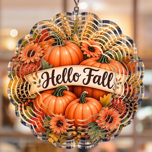 Peut inclure: Un carillon à vent circulaire en métal arborant un thème automnal vibrant avec des citrouilles orange, des tournesols, des épis de blé et des pommes de pin. Une bannière crème affiche le texte Hello Fall en brun sur un fond à carreaux.