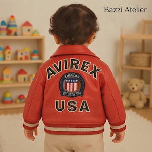 May include: A red leather bomber jacket featuring the text AVIREX and USA in black lettering on the back. A circular patch with a shield design, stars, and the text AMERICAN AUTHENTIC USA is centered. The jacket has ribbed cuffs and a ribbed hem.
