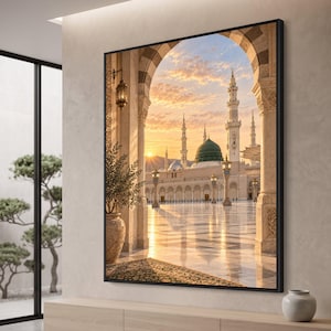 May include: A framed wall art print depicting a view through a stone archway of the Al-Masjid an-Nabawi mosque at sunset. The scene features a prominent green dome, tall minarets, and a reflective marble courtyard illuminated by golden light.