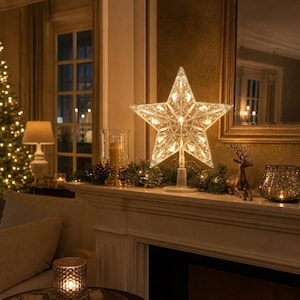 May include: A five-pointed star tree topper featuring a clear, intricate filigree design with internal warm white LED lights. The star is mounted on a sturdy, cylindrical base, emitting a soft, glowing illumination across its metallic frame.