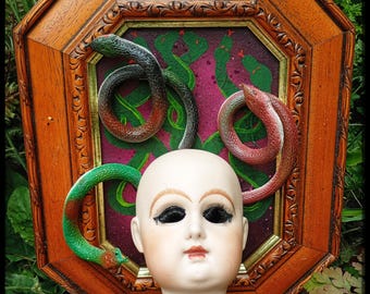 Imagem 3D da Medusa com cobras e rosto de boneca.