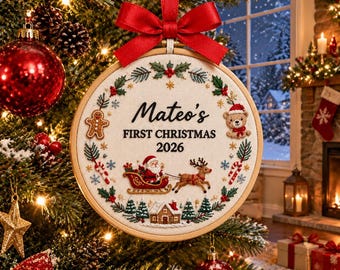 Può includere: Una decorazione natalizia in un telaio da ricamo in legno con tessuto color crema e la scritta Mateo's FIRST CHRISTMAS 2026. Il ricamo raffigura agrifoglio, un omino di pan di zenzero, un orsetto e Babbo Natale su una slitta con una renna.