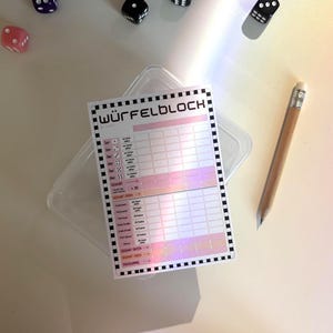 Könnte beinhalten: Ein rechteckiger Punkteblock mit der Aufschrift WÜRFELBLOCK und einem schwarz-weiß karierten Rand, der ein Raster für Würfelspiele enthält. Das Papier hat eine holografische Oberfläche und liegt neben einem Holzbleistift und verstreuten Würfeln.