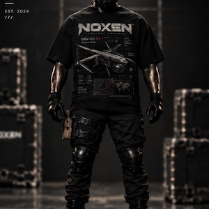 Könnte beinhalten: Ein schwarzes T-Shirt mit dem weißen Text NOXEN TACTICAL APPAREL und einer Grafik einer UAV-01 Aufklärungsdrohne mit technischen Schaltplänen und einer Weltkarte. Das T-Shirt wird mit einer schwarzen taktischen Hose, Knieschonern, Handschuhen und einem Helm getragen.