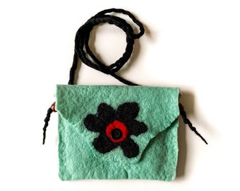 May include: A small, teal felt bag with a black flower design and a red button. The bag has a black braided strap.