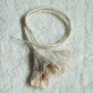 May include: A white and pink felted flower headband with a ruffled edge.