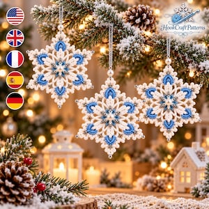 May include: Three intricate snowflake ornaments crafted from white and blue cord, featuring a central pearl bead and silver accents. Each ornament hangs from a silver chain, displaying a complex, symmetrical, star-shaped macrame design.