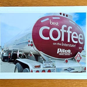 Könnte beinhalten: Foto eines großen, silbernen Tanklastwagens mit einem weinroten Tank. Auf dem Tank steht in weißer Schrift "best coffee on the Interstate!". Das Logo der Pilot Travel Centers ist sichtbar. Ein Nummernschild ist sichtbar.