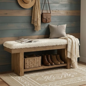 May include: A wooden entryway bench with a white sherpa-textured seat cushion, featuring a lower shelf holding a woven basket and two pairs of brown leather boots. A cream-colored throw blanket drapes over the side of the bench.