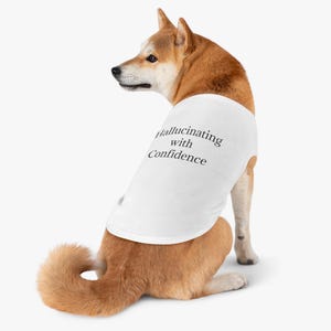 May include: A white dog tank top featuring the black text Hallucinating with Confidence printed on the back. The garment is worn by a tan and white Shiba Inu dog facing away from the viewer, showcasing the sleeveless design and fabric.