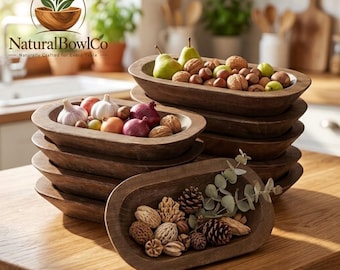 May include: A stack of oval-shaped dark brown wooden bowls. The top bowl contains green pears and walnuts. The middle bowl holds garlic bulbs and red onions. The front bowl is filled with assorted pinecones and dried seed pods on a wooden surface.