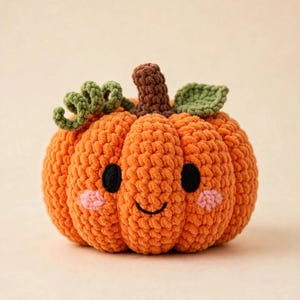 May include: A crocheted orange pumpkin plush with a brown stem, green curly tendrils, and a green leaf. The pumpkin features a stitched face with two round black eyes, a curved black mouth, and two small pink circular patches on the cheeks.