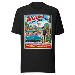 Puede incluir: Una camiseta negra con un estampado gráfico de un cartel de bienvenida de estilo vintage. La ilustración muestra un coche azul con una familia, un agente de policía y el texto Welcome to Town, Riverton y Your journey has been tracked.