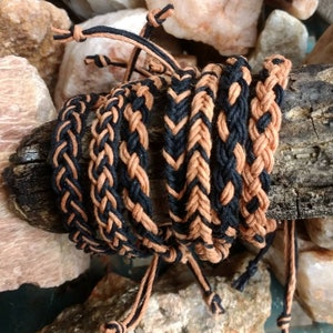 Könnte beinhalten: Ein Set aus sechs geflochtenen Armbändern in Schwarz und Braun. Die Armbänder sind aus geflochtener Schnur gefertigt und haben ein schlichtes, minimalistisches Design.