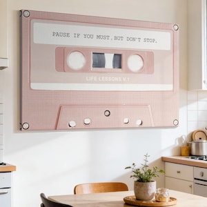 May include: A rectangular canvas wall art print featuring a stylized light pink cassette tape. The text PAUSE IF YOU MUST, BUT DON'T STOP. is printed in black on the upper label, and LIFE LESSONS V.1 is printed on the lower label area.